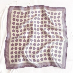 Close-up of light purple polka dot silk scarf with elegant satin finish on white silk