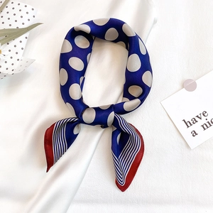 Navy blue silk scarf with white polka dots and red borders on white fabric background