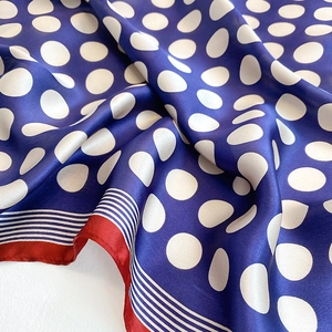 Detail of navy blue silk scarf with white polka dots and delicate red hand-rolled edges