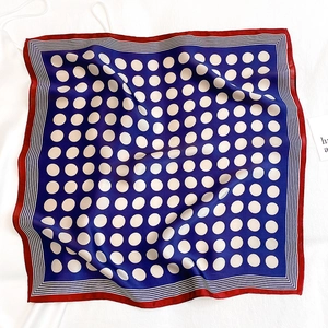 Detail shot of navy blue polka dot silk scarf with elegant red stitched edges