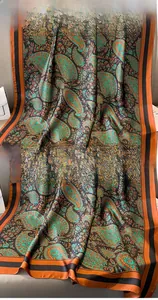 Detailed view of paisley print silk scarf with peacock green base and neat hemmed edges