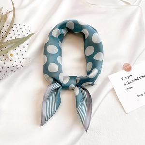 Close-up of a blue polka dot silk scarf with striped edges and an elegant glossy finish