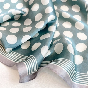 Detail view of dark green silk scarf with large white polka dots and striped edges