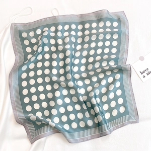 Close-up of silk-like satin neck scarf featuring white polka dots and striped borders