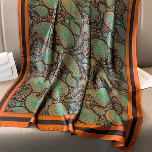 Detail of paisley silk scarf with orange and teal floral patterns draped on a sofa