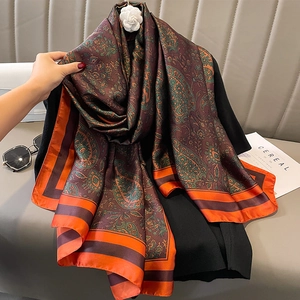 Coffee brown paisley silk shawl with orange borders styled on a black sweater