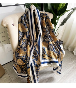 Detailed view of navy blue and yellow paisley print silk-like scarf draped on a chair