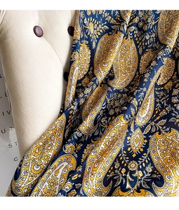 Macro detail of navy blue and yellow paisley print on elegant silky scarf fabric