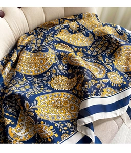 Close-up of navy and yellow paisley silk scarf elegantly displayed on a fabric sofa