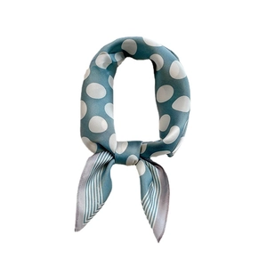 Blue-green silk scarf with white polka dots and stripe trim in a looped knot