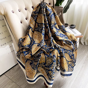 Blue and yellow paisley silk scarf elegantly draped on a chair in a home setting