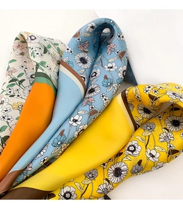 Détail de foulards en soie à motifs floraux orange, bleu et jaune avec des marguerites