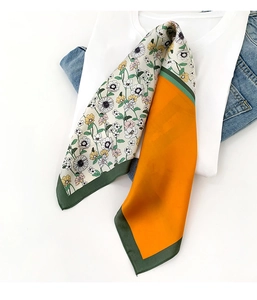 Détail d'un foulard en soie double face avec motif marguerites et revers orange vif