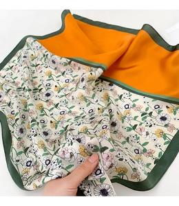 Gros plan détaillé du foulard en soie double face avec imprimé marguerites et orange vif
