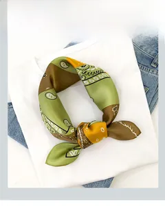 Detail of silk square scarf featuring green and brown paisley print on white shirt
