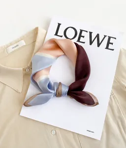 Dettaglio di un foulard in satin a blocchi di colore rosa e blu su una camicia beige