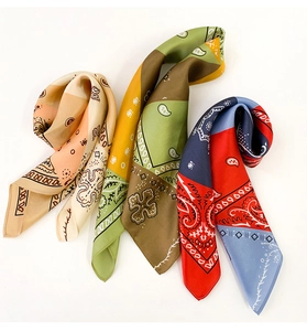 Detailed view of three paisley print square silk scarves in assorted color palettes
