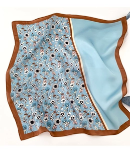 Détail d'un carré de soie bleu avec imprimé fleuri et bords cousus marron