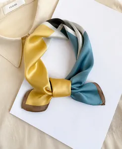 Dettaglio di elegante foulard in raso con blocchi di colore geometrici giallo e grigio
