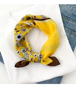 Détail d'un foulard en soie jaune avec motifs de marguerites et bordure contrastée