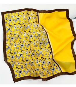 Détail macro du foulard en soie jaune avec imprimé marguerite et bordure marron