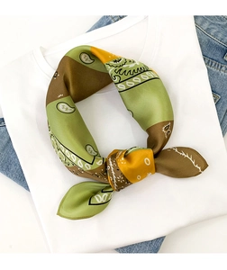 Close-up of knotted paisley print silk scarf with green and orange tones on white shirt