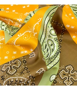 Close-up of paisley pattern silk scarf with olive green and orange twill fabric details