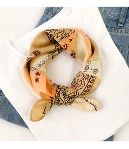 Detail of vintage paisley silk scarf tied in a knot on a white shirt and denim jeans