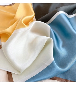 Dettaglio macro di un foulard in raso con texture liscia e cuciture a blocchi di colore