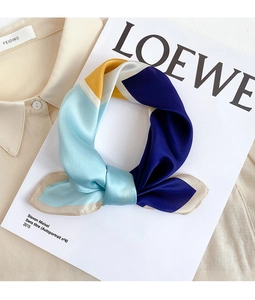 Dettaglio del foulard in raso colorato con motivi geometrici su una camicia beige