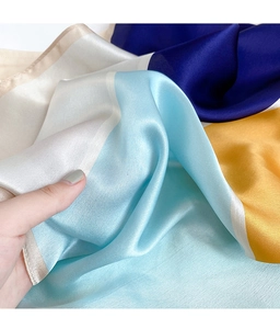 Dettaglio di sciarpa in seta color-block con lucentezza satinata e bordi arrotolati
