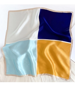 Dettaglio di un foulard quadrato in seta con design color block e finitura satinata