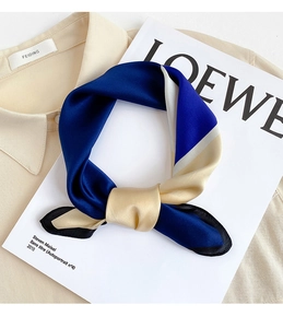 Dettaglio foulard in satin color-block blu e beige annodato a fiocco su camicia