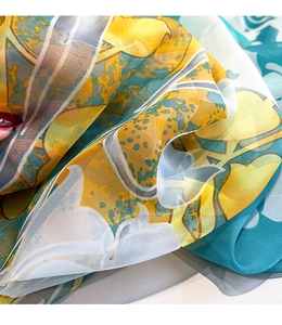 Detailed macro view of sheer floral chiffon scarf fabric with vibrant yellow and blue patterns