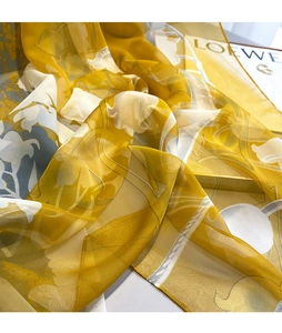Detailed texture of lightweight yellow floral silk scarf with soft drape and rolled edges