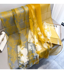Detailed view of yellow and grey floral silk scarf draped elegantly on a chair