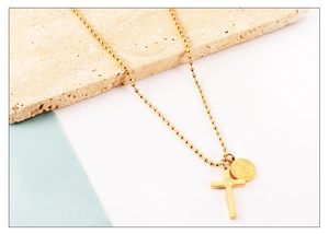 Détail du collier à billes plaqué or 18K avec croix et médaille religieuse sur pierre