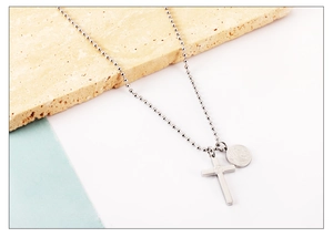 Gros plan d'un collier à billes argenté avec croix polie et pendentifs en relief rond