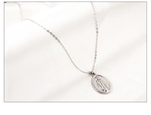 Détail d'un collier médaille religieuse en argent sur un élégant fond en satin blanc