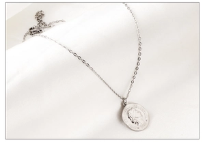 Vue macro d'un collier pendentif pièce en acier plaqué or 18 carats sur soie blanche