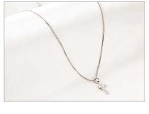 Gros plan d'un pendentif croix en argent avec oxydes de zirconium sur chaîne fine