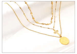 Vue détaillée du collier multicouche plaqué or avec croix et médaille de la Vierge