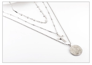 Détail d'un collier triple rang en acier inoxydable avec croix et médaillon de la Vierge