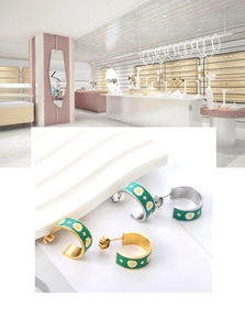 Detail of C-shaped enamel earrings with daisy pattern in gold and silver finish