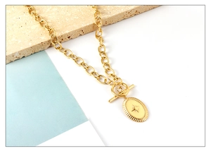 Detail of gold starburst oval pendant on chunky link chain with stylish OT toggle clasp