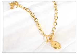 Detailed close-up of golden chunky oval link chain with OT toggle clasp and star pendant