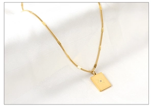 Detail of gold oval pendant necklace with engraved starburst and central zircon inlay