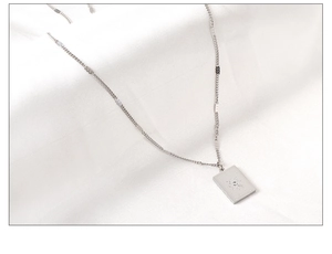 Macro shot of silver oval sun pendant necklace with star motif on white satin fabric