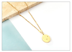 Detail of gold oval pendant with celestial moon and star engraving and inlaid rhinestones