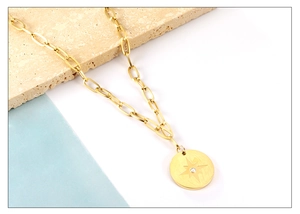 Detail of gold oval starburst pendant with crystal on paperclip chain necklace